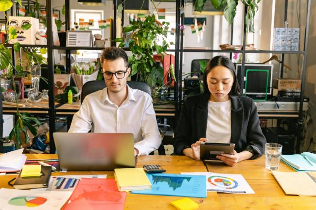 Zu sehen sind zwei Mitarbeiter vor Laptops die womöglich gerade an Strategien für mehr Nachhaltigkeit im Unternehmen arbeiten. Bild: Pexels/Antoni Shkraba Studio