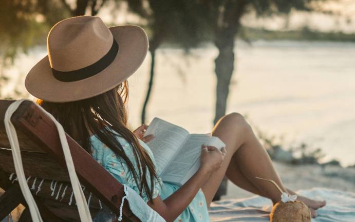 Zu sehen ist eine Frau in einer Hängematte die ein Buch liest und digital Detox macht. Bild: Pexels/Taryn Elliott