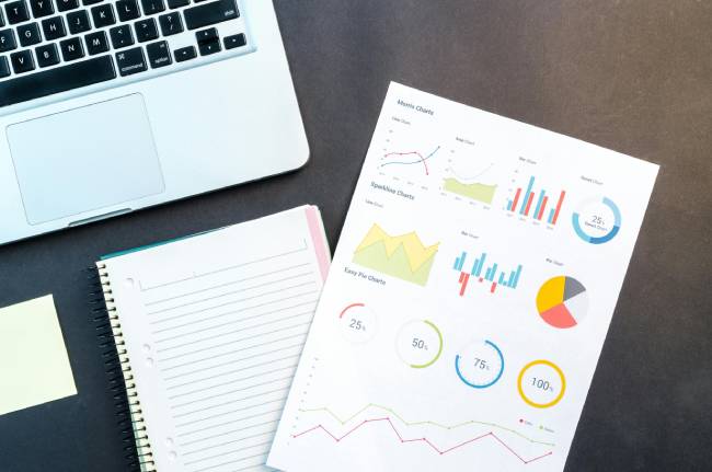 Zu sehen ist ein laptop und ausgedruckte Reportings und Grafiken die den Erfolg von Open Source Software symbolisieren sollen. Bild: Pexels/Lukas