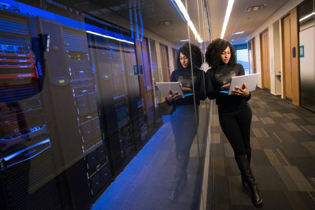 Zu sehen ist eine Frau vor einem Serverraum wo eventuell ein Security Operations Center hinter steckt welches für die Cybersicherheit im Unternehmen sorgt. Bild: Pexels/Christina Morillo