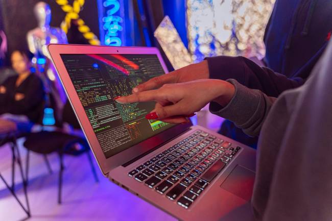 Zu sehen ist ein Laptop mit zwei Personen davor die womöglich gerade im Security Operations Center arbeiten und Cyberbedrohungen erkennen. Bild: Pexels/Antoni Shkraba Studio