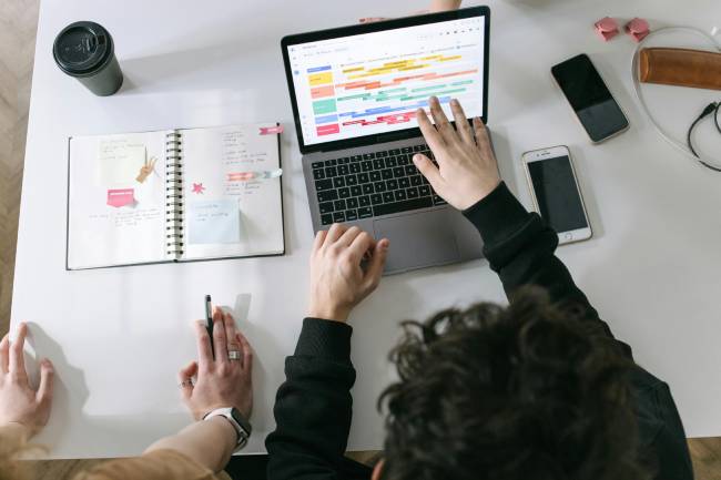 Zu sehen sind zwei Personen vor einem Laptop mit einem Kalender daneben die womöglich gerade ihre Brückentage 2026 für ihren Urlaub planen. Bild: Pexels/Ivan Samkov