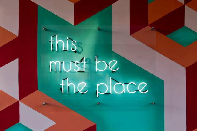 Zu sehen ist ein Schriftzug mit this must be the place was auf eine positive Unternehmenskultur hinweisen soll was wider um auch durch die eigene Karriereseite kommuniziert werden kann. Bild: Pexels/Tim Mossholder