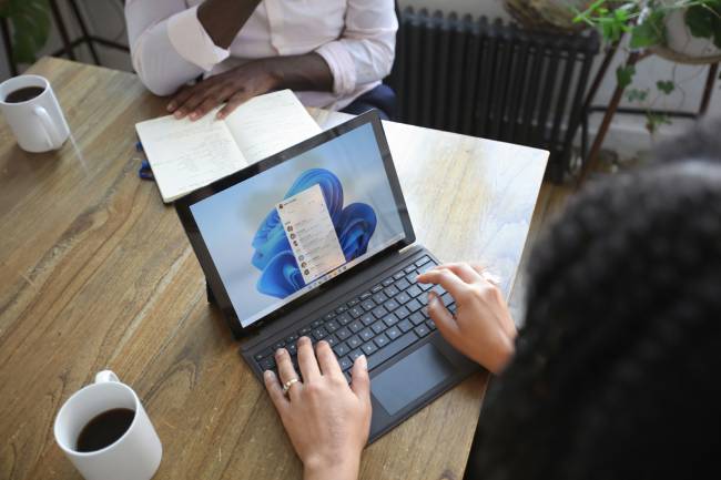 Windows 11 25H2 bringt mehr Tempo, smarte KI-Funktionen und spürbare Verbesserungen im Arbeitsalltag das sollen hier zwei Mitarbeiter vor ihren Windows Microsoft Laptops verdeutlichen. Bild: Unsplash/Windows